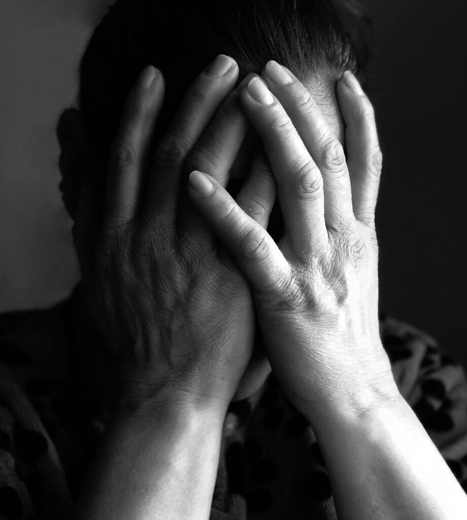 extreme close up of a woman covering her face denoting shame