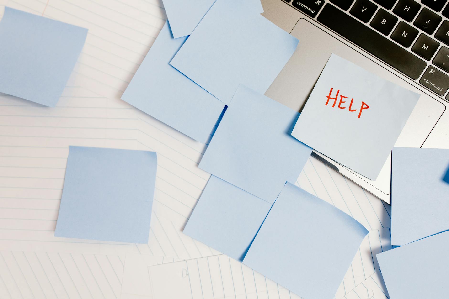 Post it notes, with one saying help in red letter on white table with a laptop